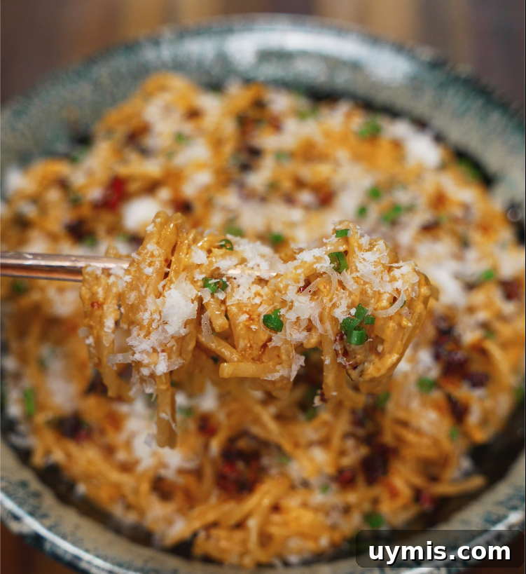 Spicy Chili Oil Pasta with Caramelized Onions 3 Close-up of a forkful of chili oil caramelized onion pasta topped with parmesan and scallions.
