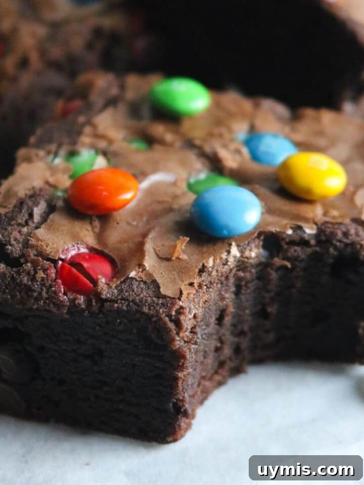 close up image of a thick, chewy m&m brownie with a bite out of it.