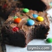 Thick and Chewy M&M Brownies Recipe 13 close up image of a thick, chewy m&m brownie with a bite out of it.