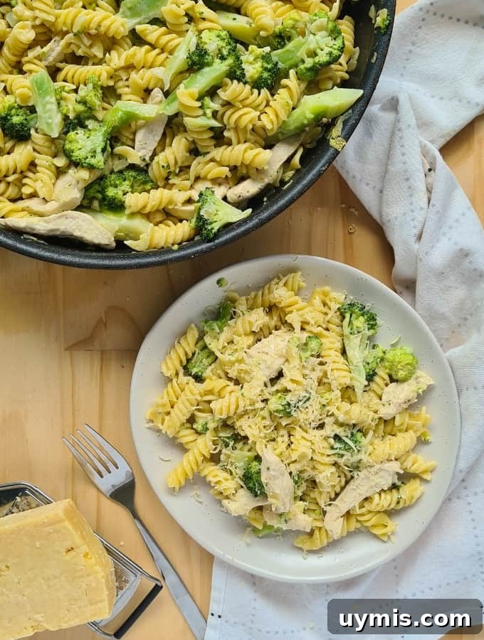 Light Chicken and Broccoli Pasta Recipe 12 A plate of cooked chicken and broccoli pasta with freshly grated parmesan cheese on top. A fork on the left and a loosely folded kitchen towel on the right side of the plate.
A cooked chicken and broccoli pasta inside a large pan/skillet on the op left hand corner of image.