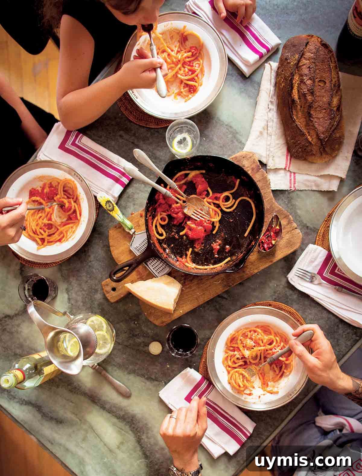 Sugo di Pomodoro Italian Tomato Sauce Recipe 2 People gathered around a cast-iron skillet on a wooden board with spaghetti and red sauce.