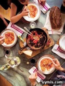 Sugo di Pomodoro Italian Tomato Sauce Recipe 9 People gathered around a cast-iron skillet on a wooden board with spaghetti and red sauce.