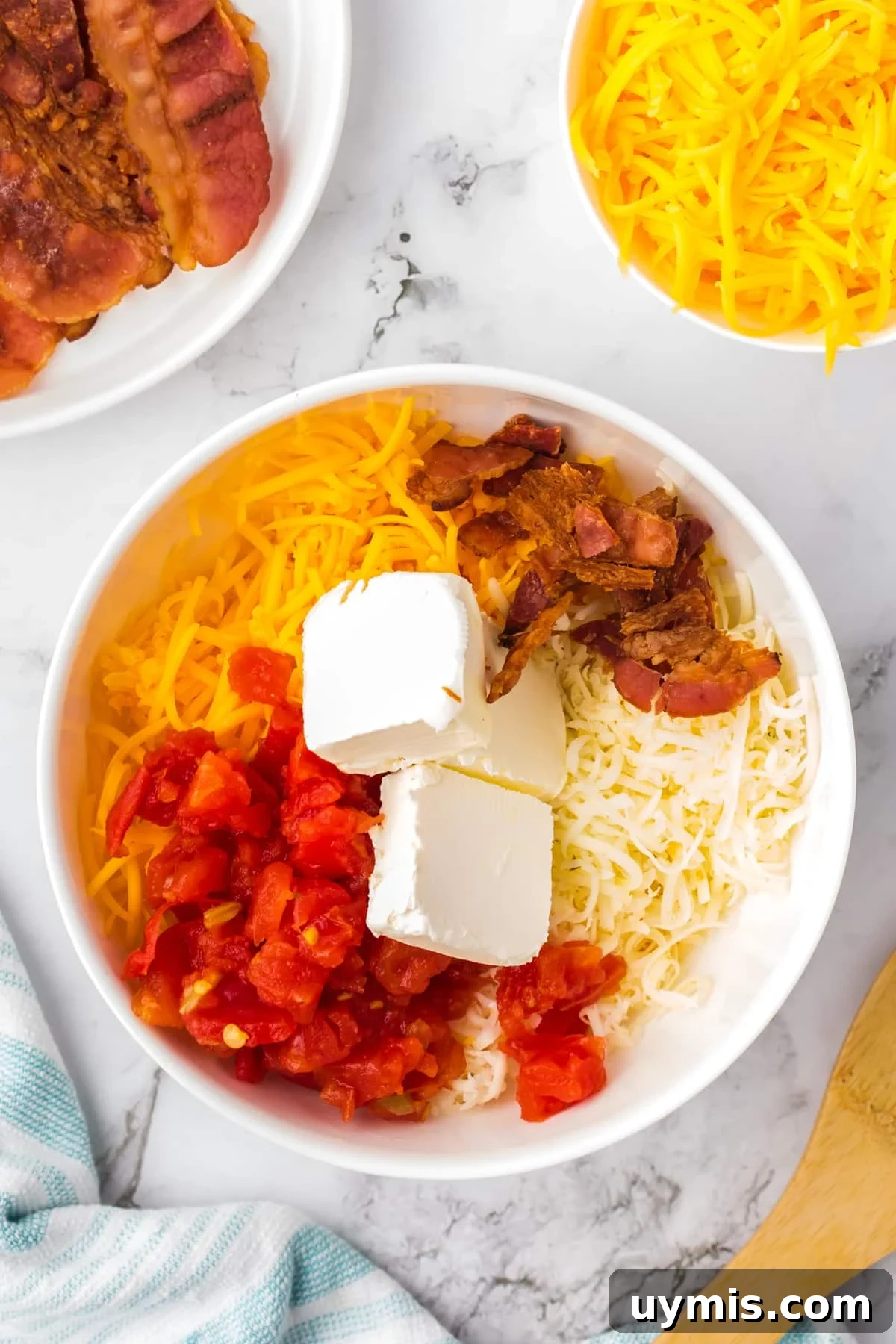 Homemade Nacho Cheese Dip Recipe 4 A large bowl filled with cheese, bacon, cream cheese, and rotel tomatoes.