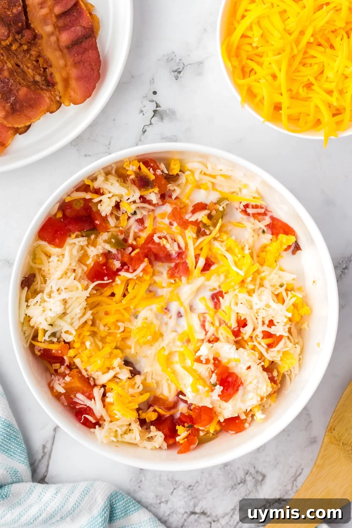 Homemade Nacho Cheese Dip Recipe 5 A large bowl with cheese and cream cheese being mixed together with bacon and rotel tomatoes.