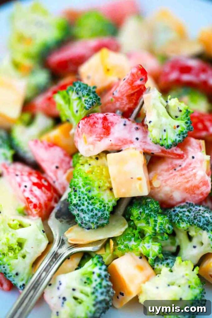 close shot of a fork of broccoli strawberry salad with cheese