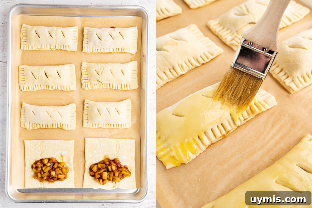 Warm Apple Hand Pies with Cinnamon and Flaky Crust 5 partially assembled apple hand pies on a baking sheet before going into the oven. Six pies are finished with two still open before folding over the puff pastry.