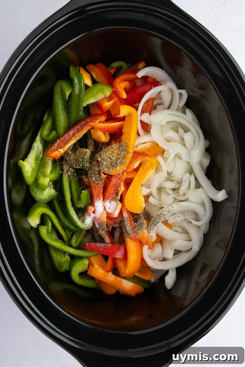 Crockpot Sausage and Peppers Recipe 6 Peppers and onion in bottom of crock pot.