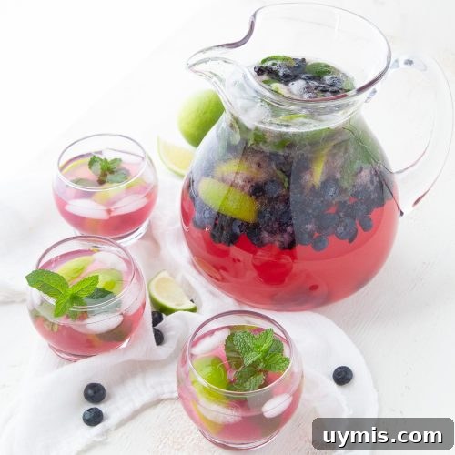 pitcher of blueberry mojitos surrounded by glasses filled with the mojito