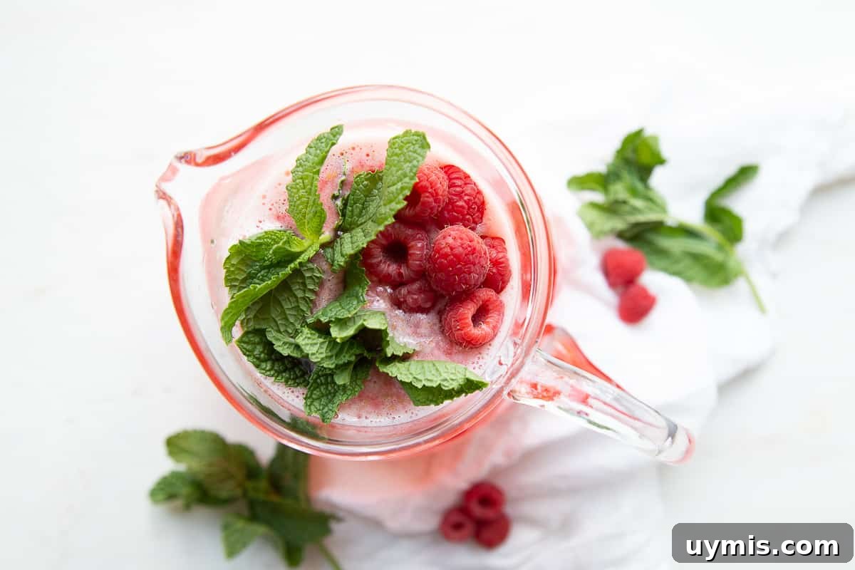 Two Ingredient Raspberry Lemonade Recipe 3 pitcher of raspberry lemonade with fresh raspberries and fresh mint.