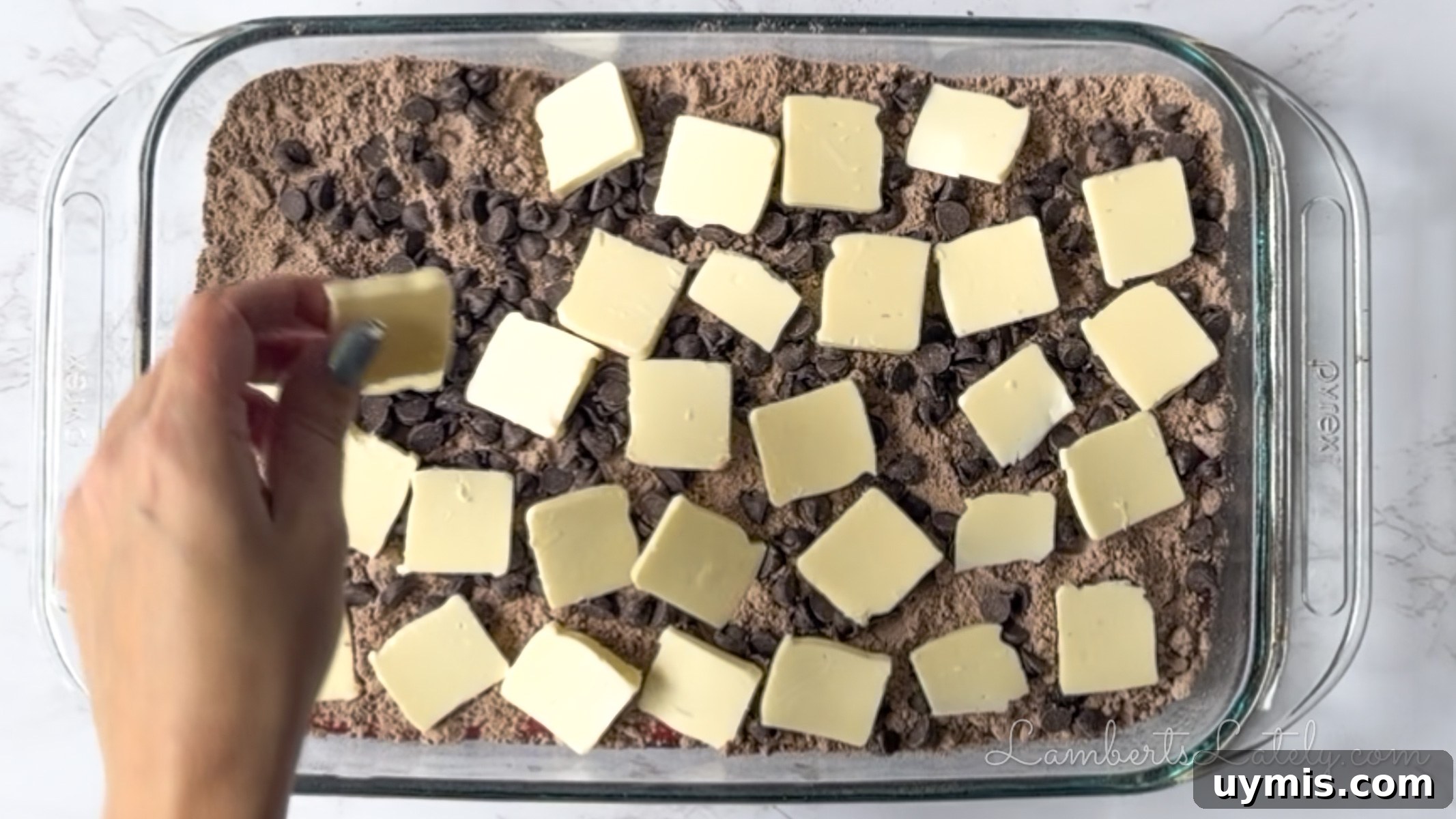 Chocolate Cherry Dump Cake Recipe 9 putting butter pats over cake mix and chocolate chips in a baking dish.