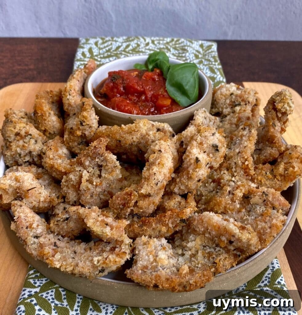 Italian Pan Fried Butterflied Shrimp Recipe 17 Plateful of pan fried butterflied shrimp with small dish of marinara dipping sauce with basil garnish, over a decorative towel.
