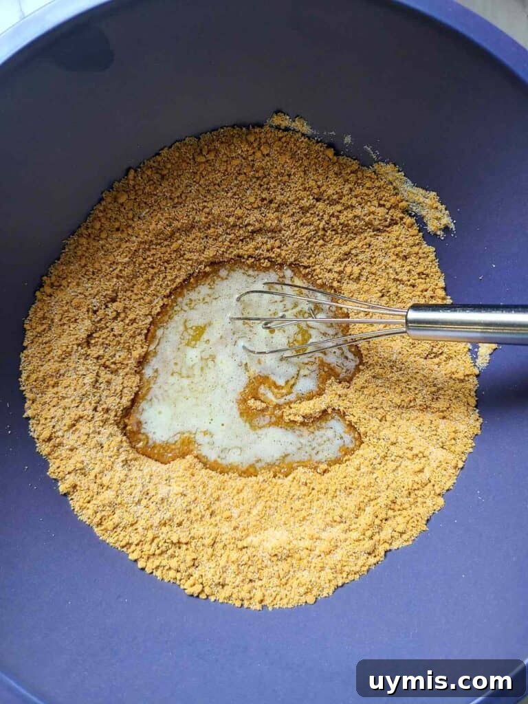 Mini Crème Brûlée Cheesecake Bites Recipe 7 In a blue bowl melted butter is added to mixture of graham cracker crumbs
