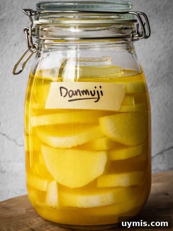 A jar with sliced daikon radish in a pickling solution, with a Danmuji label.