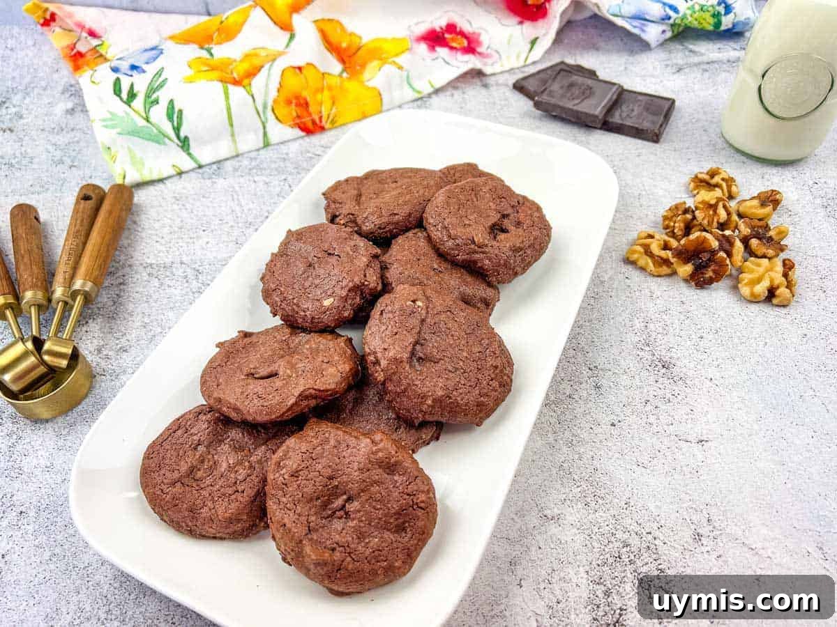 27 Chocolate Desserts You Can't Keep at Home 20 A plate of chocolate cookies with walnuts and chocolate pieces on the side.