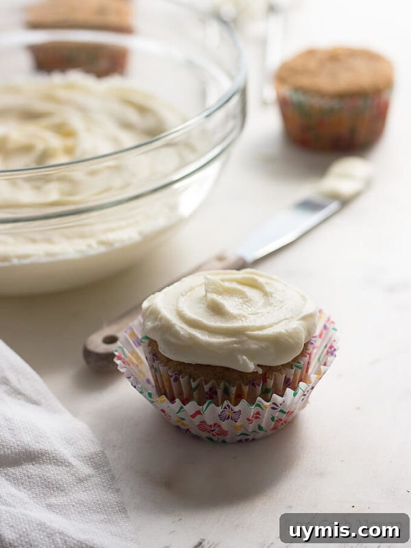 Low-Carb Sugar-Free Cream Cheese Frosting Recipe 3 Cupcake with silky sugar free cream cheese frosting; bowl and spatula in background.
