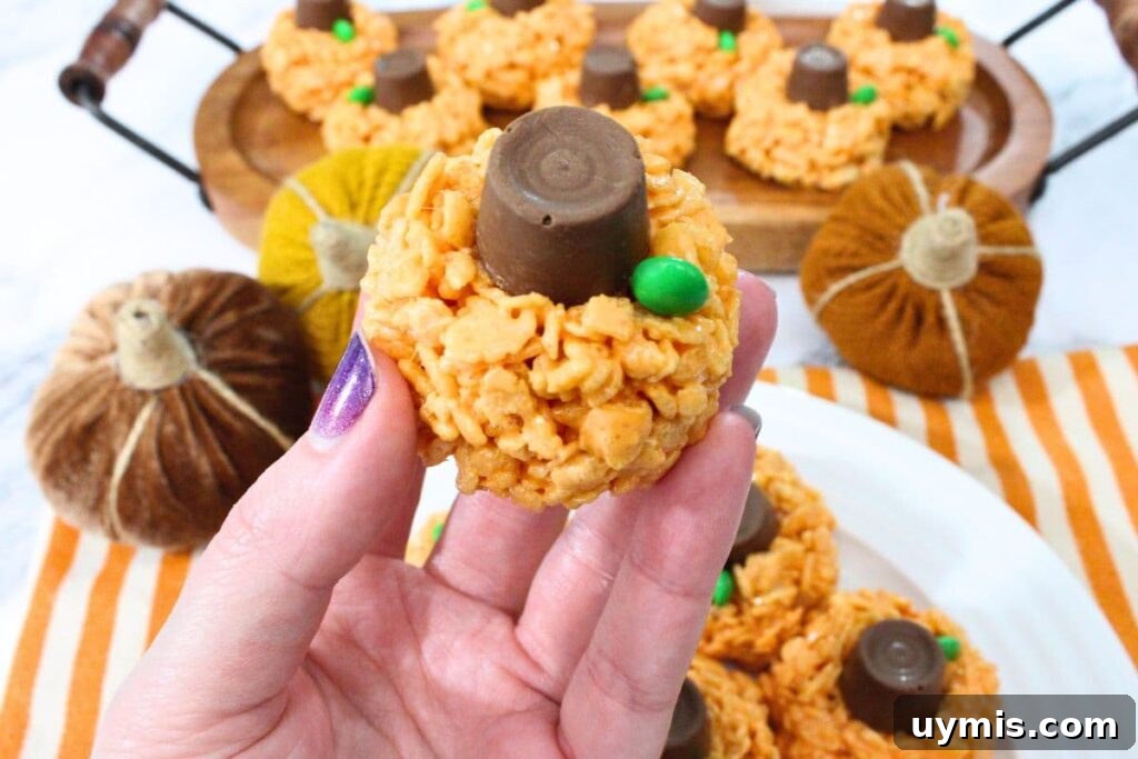 Fall Pumpkin Rice Krispie Treats with Rolos 3 holding up a gooey pumpkin rice krispie treat