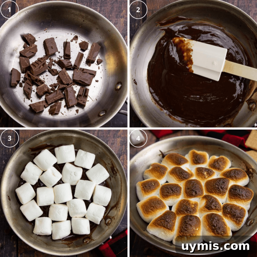 a steel pan with chocolate chunks being melted then topped with marshmallows that get toasted.