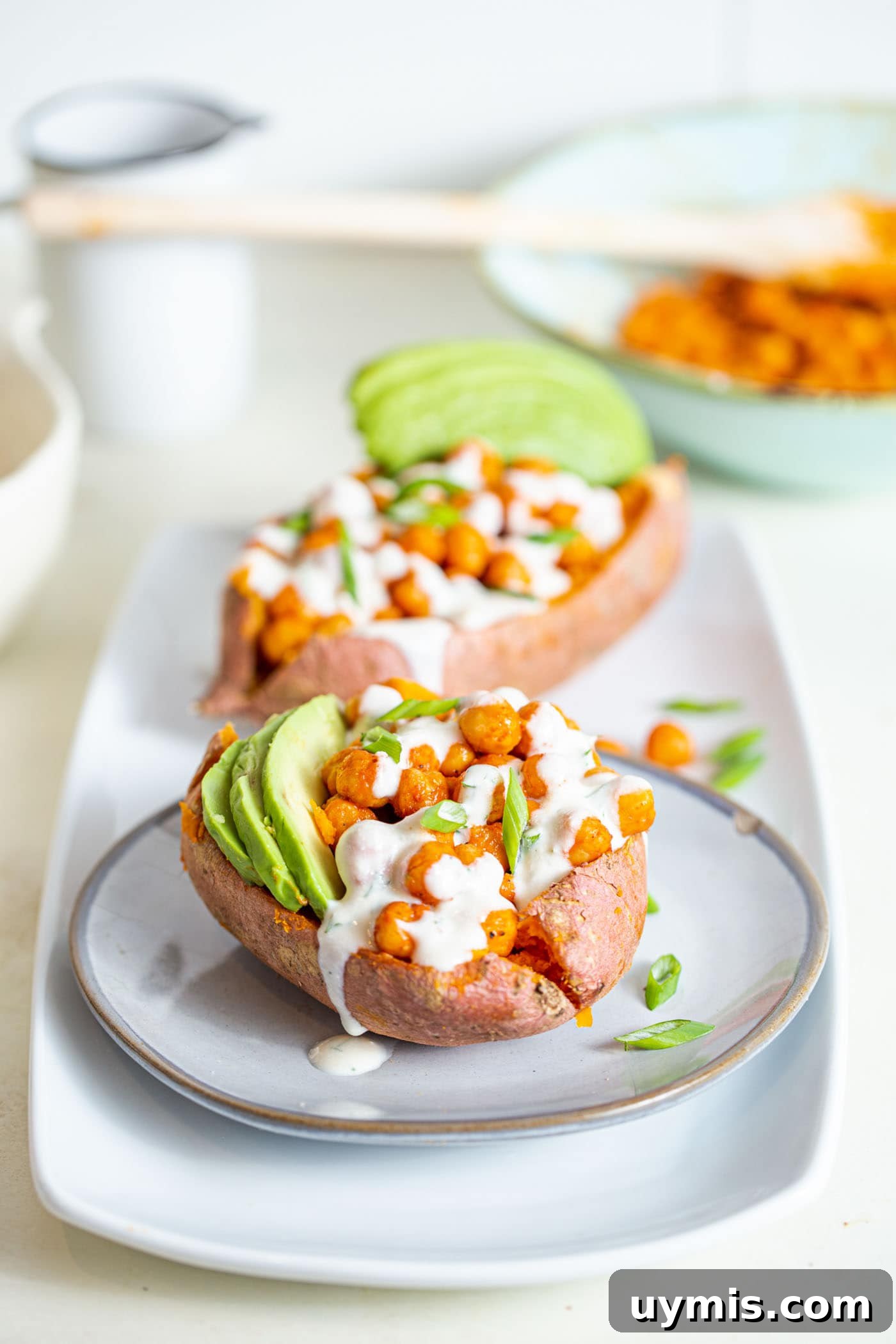 Spicy Buffalo Chickpea Stuffed Sweet Potatoes 2 Sweet potato stuffed with buffalo chickpeas and avocado, topped with white sauce.
