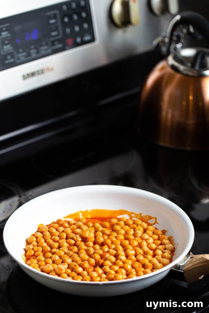 Spicy Buffalo Chickpea Stuffed Sweet Potatoes 3 A skillet of buffalo chickpeas on a black stovetop.