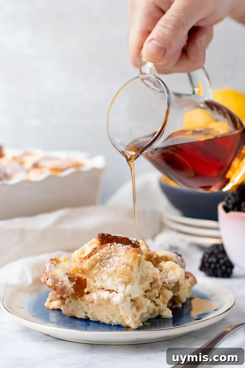 Lemon Cheesecake French Toast Casserole Recipe 5 a small jug of syrup pouring a drizzle over a serving of lemon cheesecake french toast