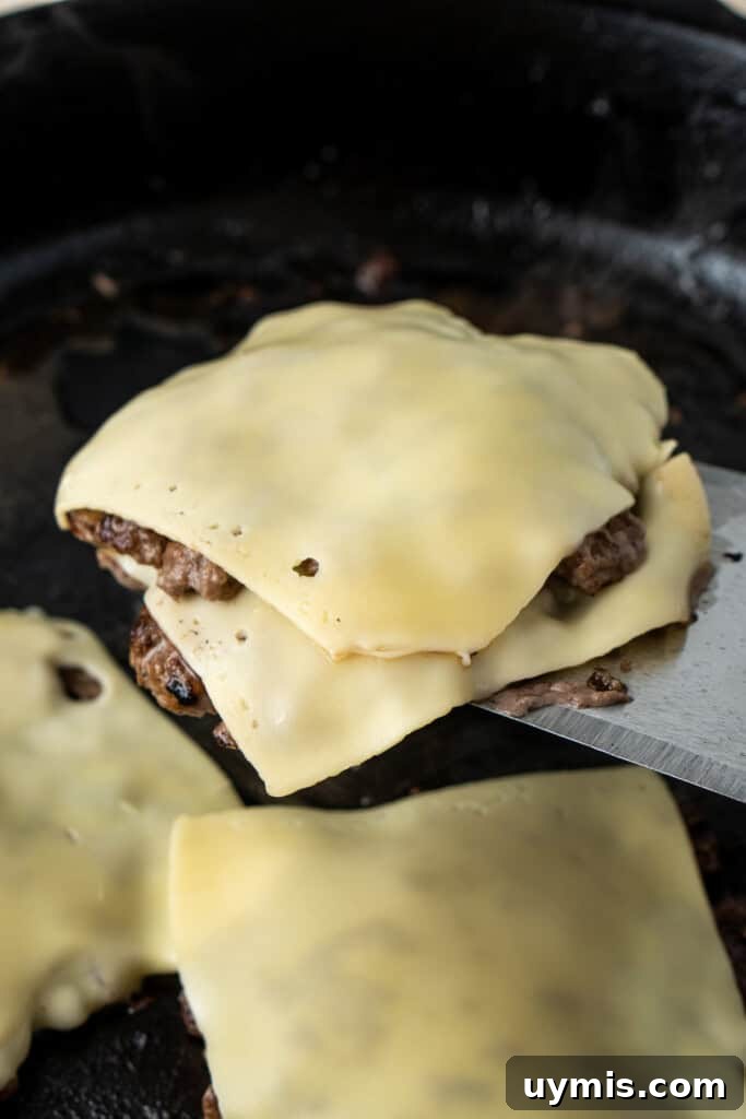 Smash Burger Recipe with Crispy Edges 10 Double stacking the burger patties with cheese on a spatula.