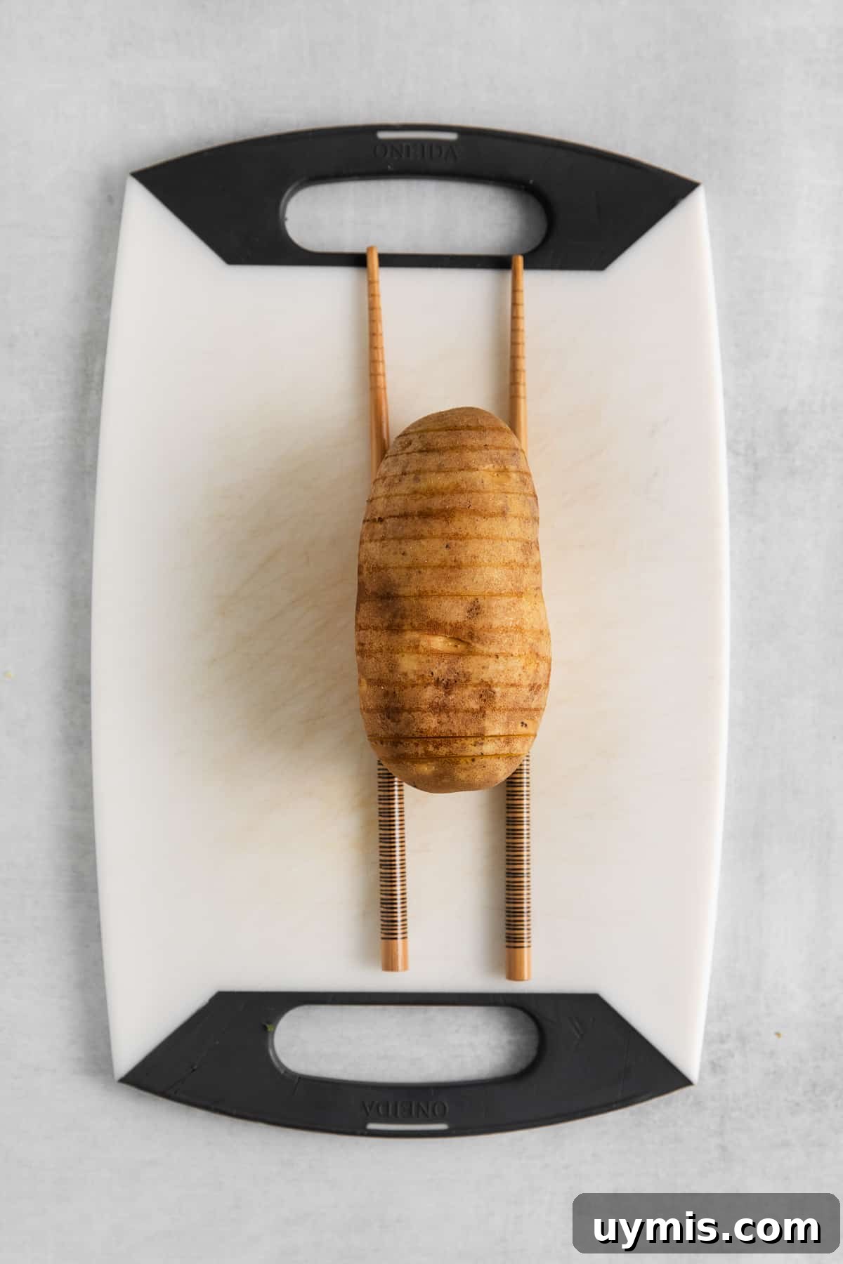 Potato sliced hasselback style on a cutting board.