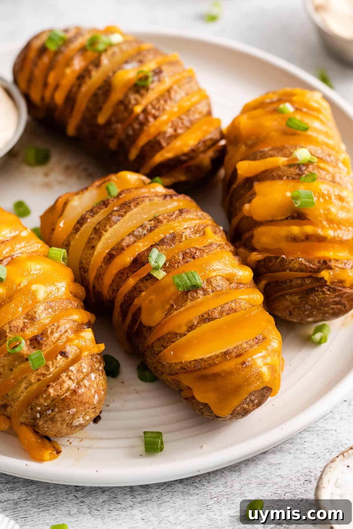 Hasselback potatoes on a plate topped with chives.