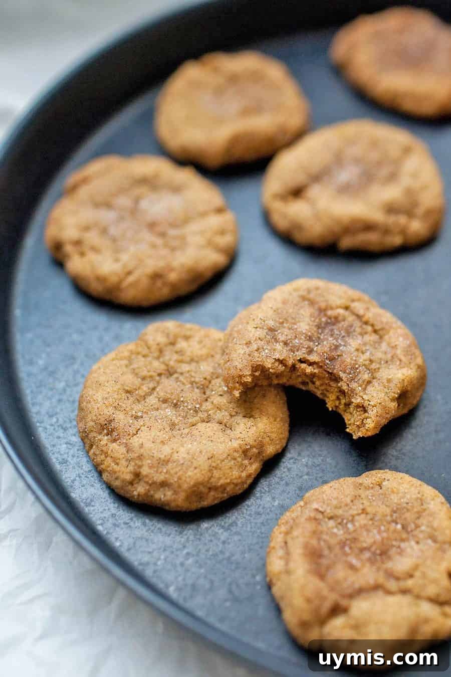 Pumpkin Snickerdoodle Cookies 8 Fresh baked pumpkin snickerdoodle cookies stacked on a surface.