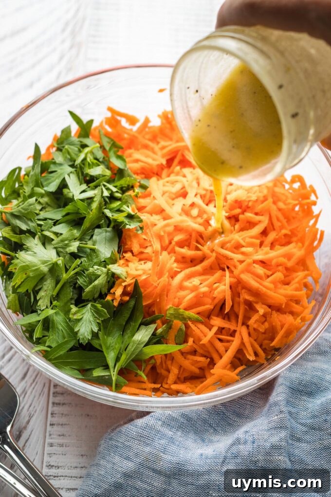 Salad dressing being poured onto a grated carrot salad.