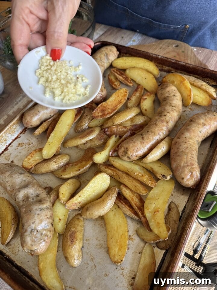 Sheet Pan Sausage and Potatoes Recipe 6 a small plate of chopped garlic above a sheet pan with sausage and potatoes