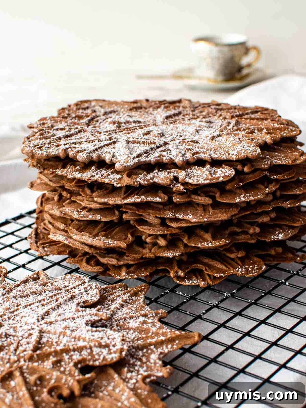 Chocolate Pizzelle Recipe 2 stack of chocolate wafer cookies on black wire rack.