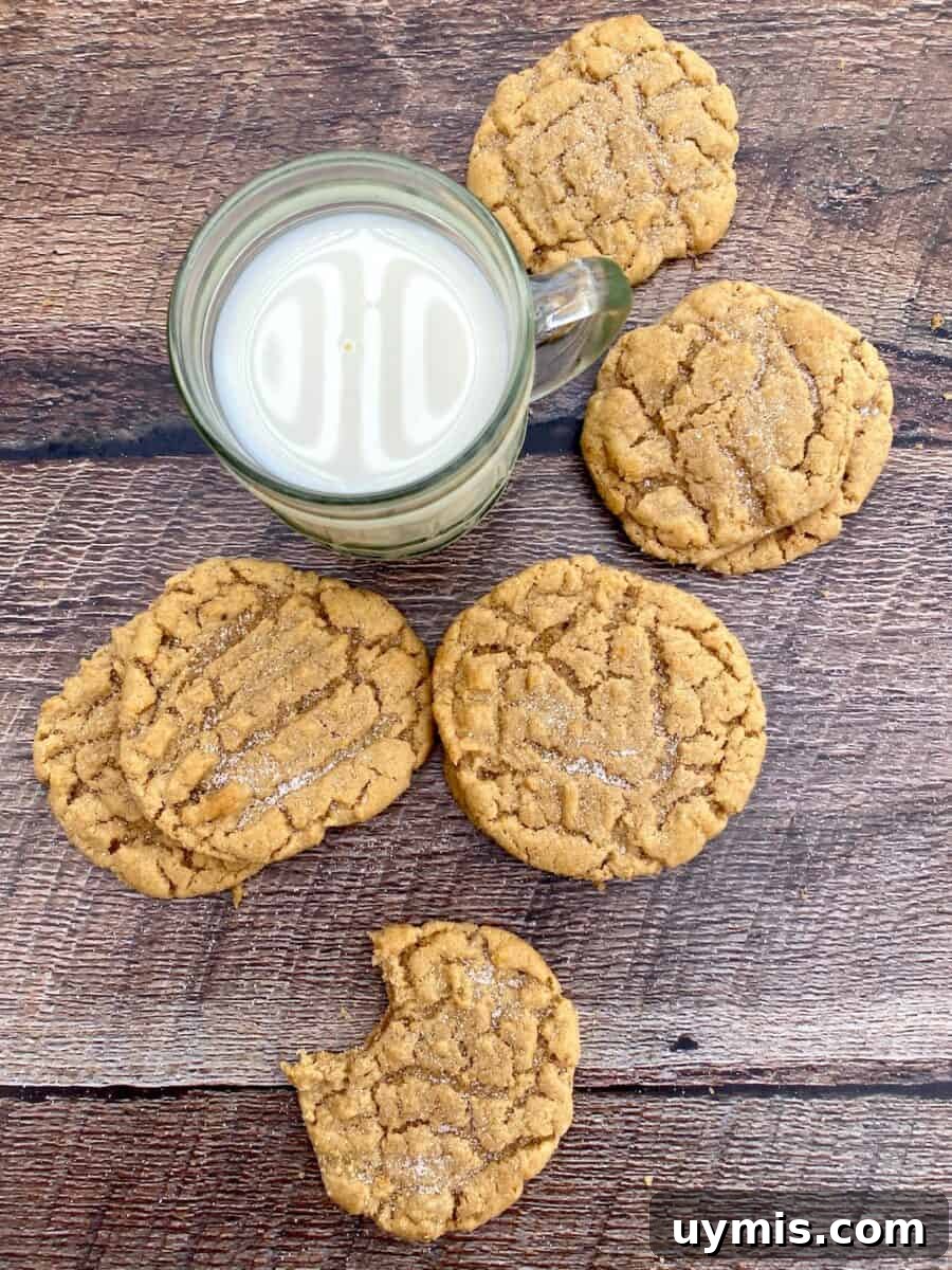 Classic Chewy Peanut Butter Cookies Recipe 9 Six peanut butter cookies arranged on a wooden board next to a glass of milk.