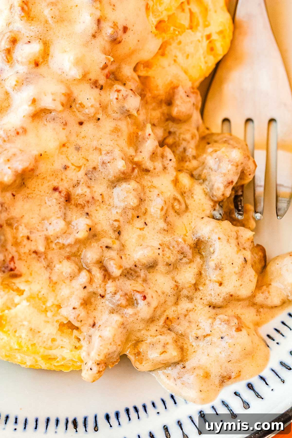 Split biscuits on a plate with sausage gravy on them.