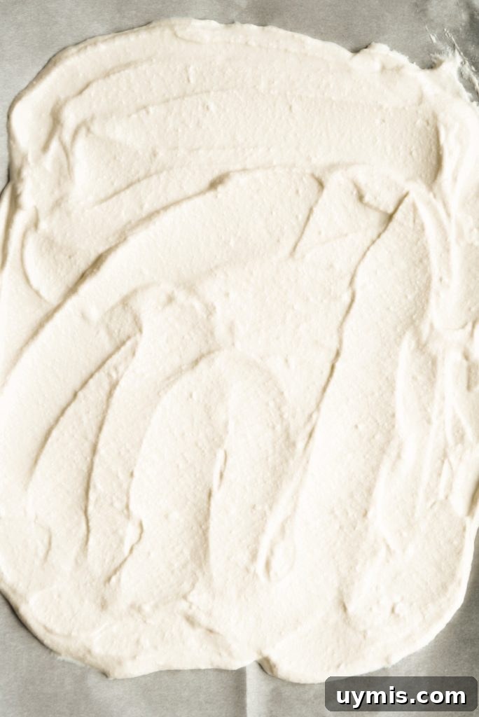 Viral High Protein Frozen Cottage Cheese Bark 7 cottage cheese and maple syrup mixture spread out on a prepared baking sheet