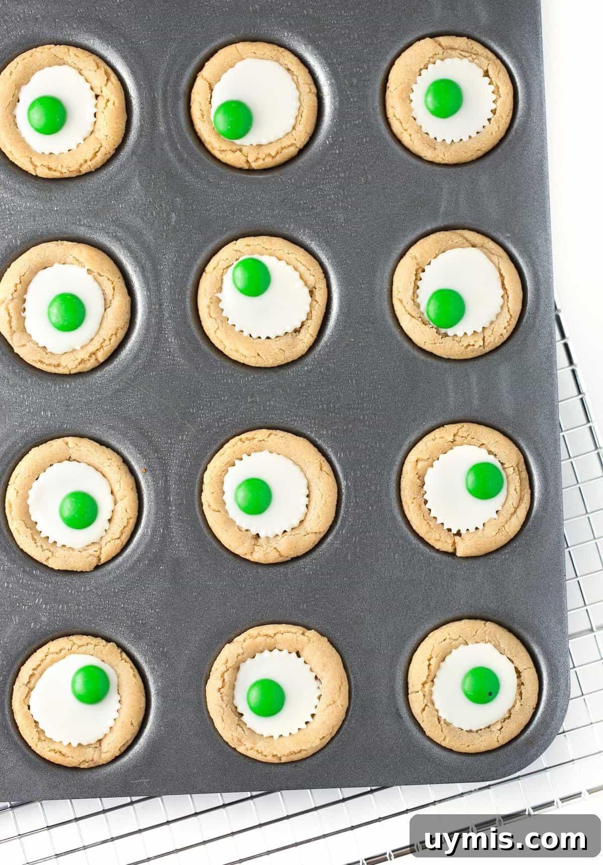 Halloween Eyeball Cookies with Peanut Butter Cups 10 Overhead photo of mini muffin tin with white chocolate peanut butter cup cookies with green M&M's in the center to look like Halloween eyeballs.