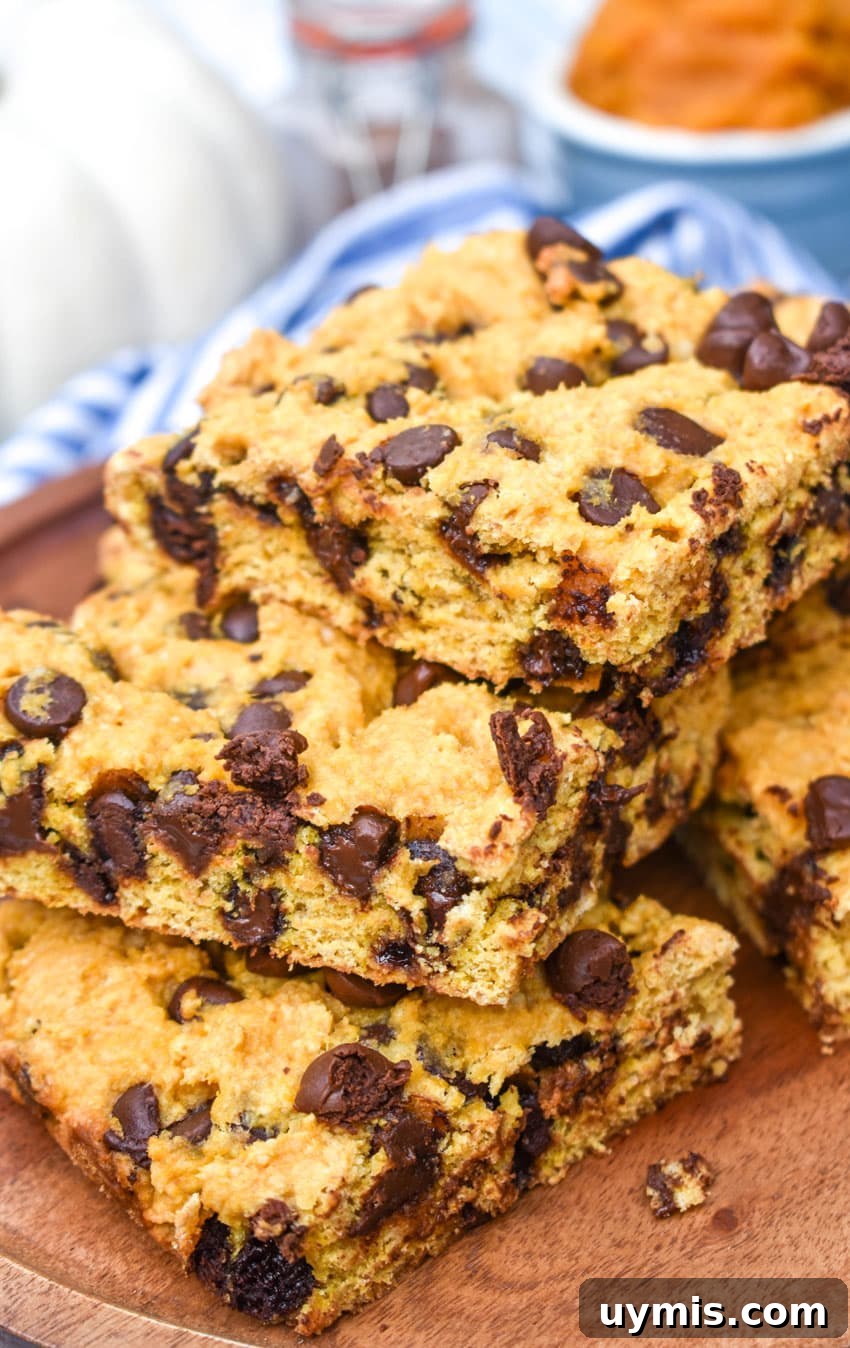 Pumpkin Chocolate Chip Cookie Bars Recipe 2 a stack of pumpkin chocolate chip cookie bar squares on a wooden cake stand