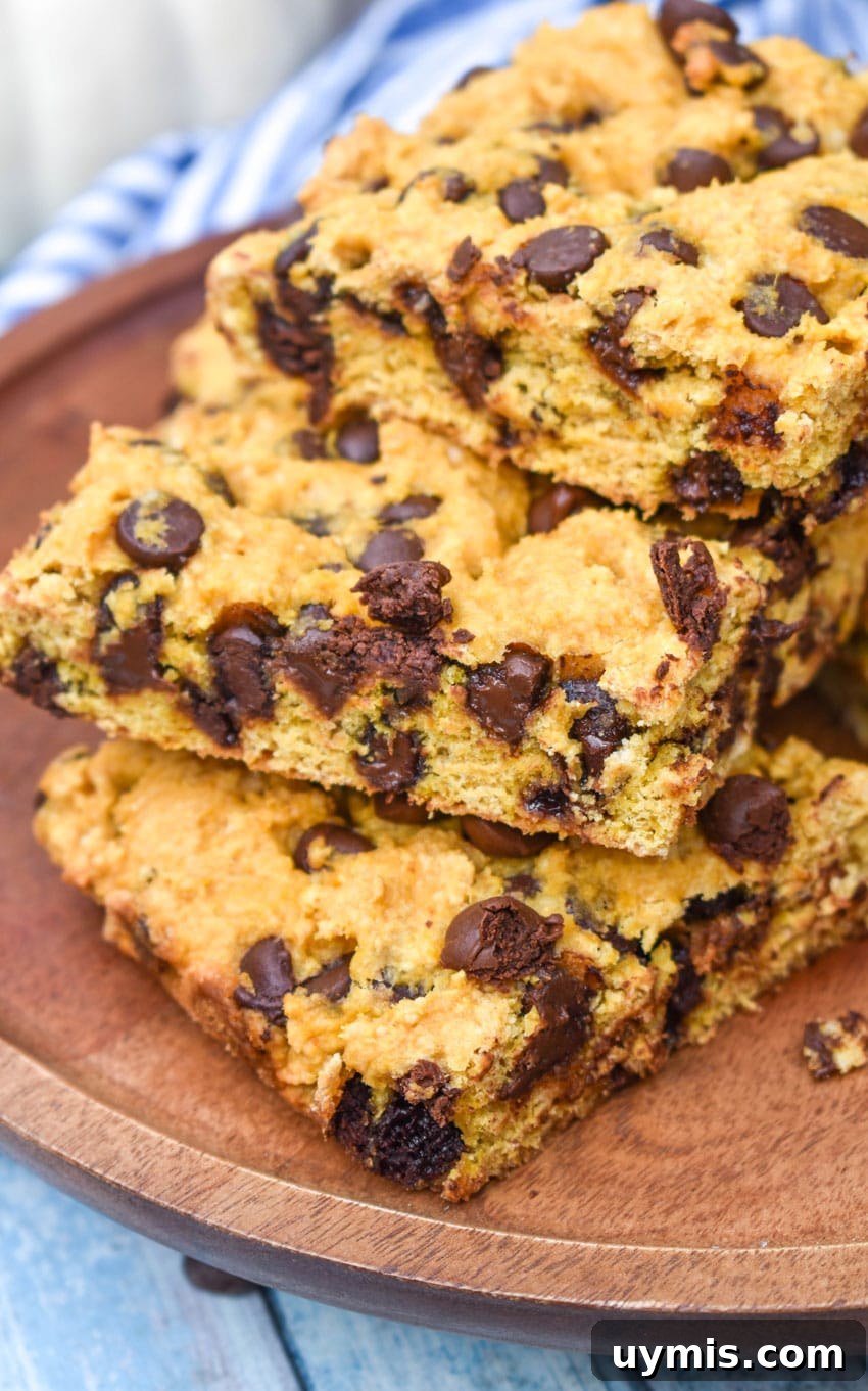Pumpkin Chocolate Chip Cookie Bars Recipe 3 a stack of pumpkin chocolate chip cookie bar squares on a wooden cake stand
