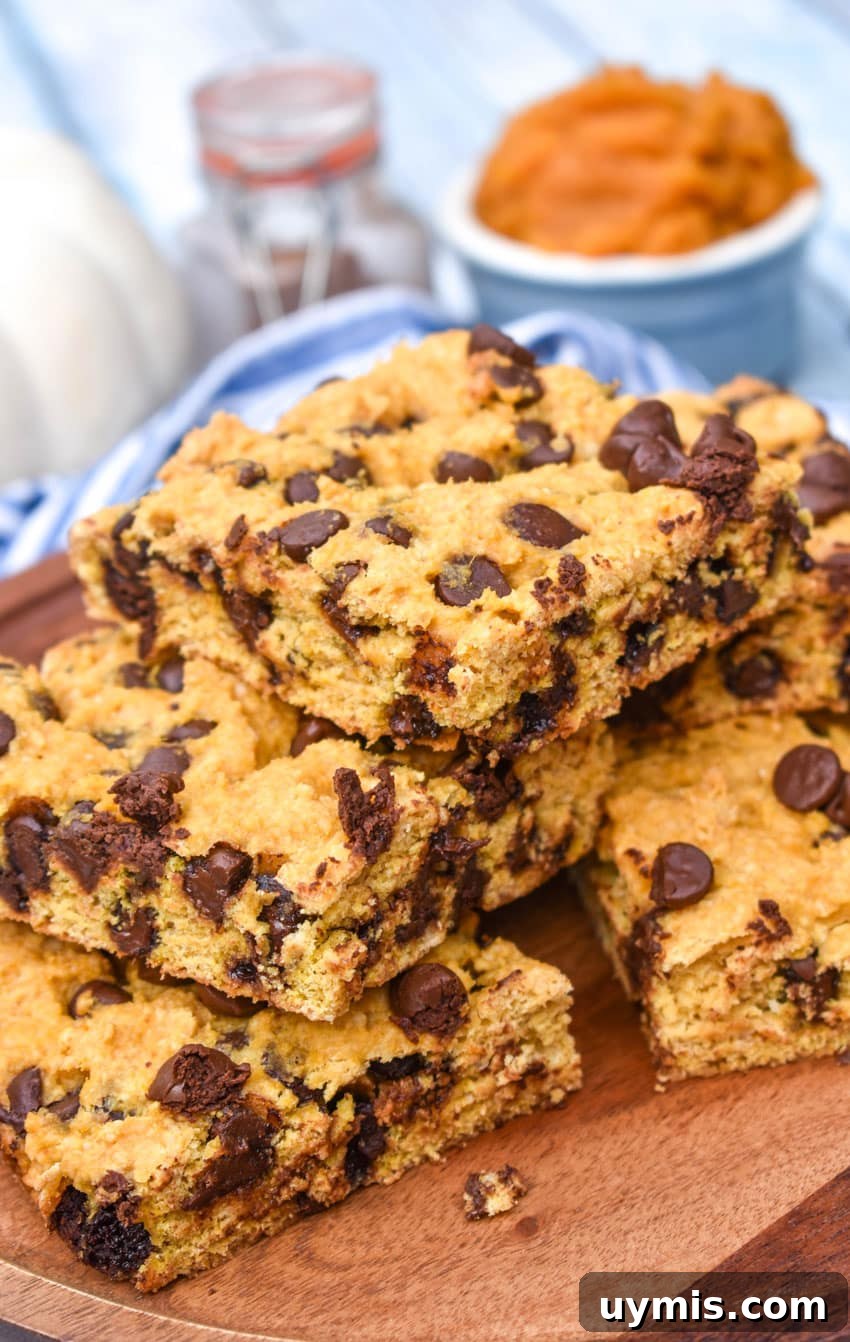 Pumpkin Chocolate Chip Cookie Bars Recipe 6 a stack of pumpkin chocolate chip cookie bar squares on a wooden cake stand