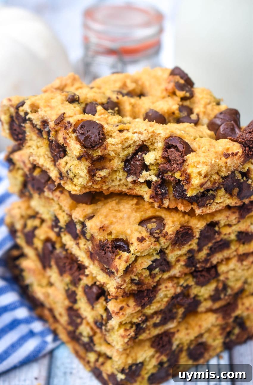 Pumpkin Chocolate Chip Cookie Bars Recipe 7 a stack of pumpkin chocolate chip cookie bar squares on a wooden cake stand