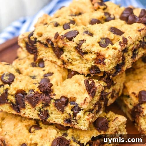 Pumpkin Chocolate Chip Cookie Bars Recipe 8 a stack of pumpkin chocolate chip cookie bar squares on a wooden cake stand