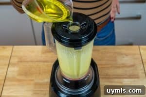 Beginning to pour the oil into the blender