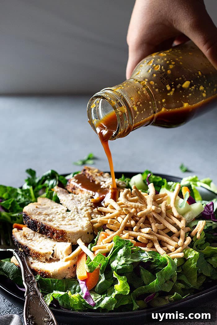 Classic Asian Salad Dressing with Sesame and Soy 5 pouring dressing over a salad.
