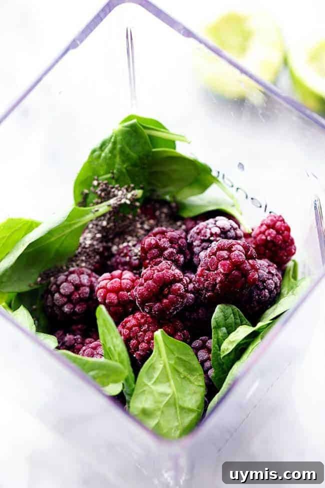 Blackberries and spinach ready to blend for a blackberry lime green smoothie. Fresh blackberries and spinach in a blender.