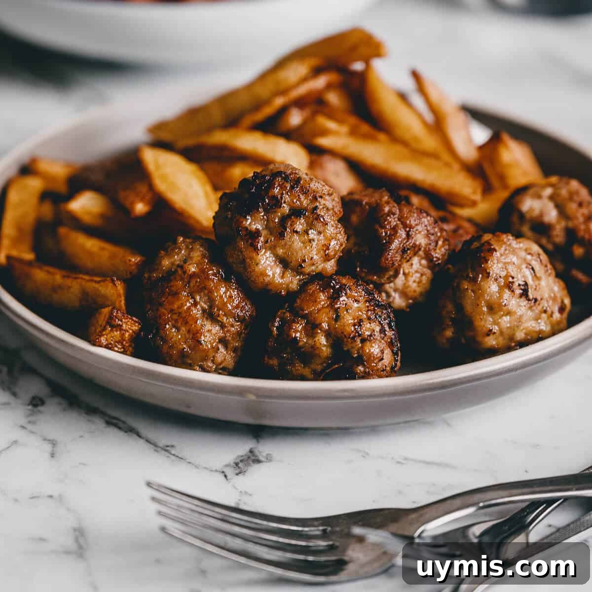 Close up of fried meatballs with french fries in the background.