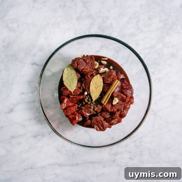 Greek Beef Stifado Recipe: Classic Slow-Braised Stew 5 Chuck steak and spices marinating in a glass bowl.