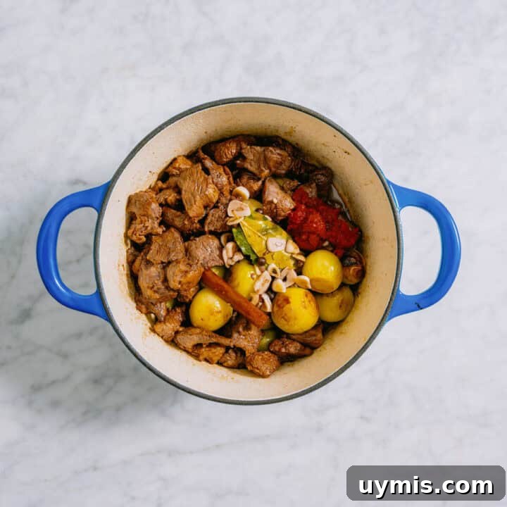 Greek Beef Stifado Recipe: Classic Slow-Braised Stew 6 Greek beef stew in a blue pot cooking.