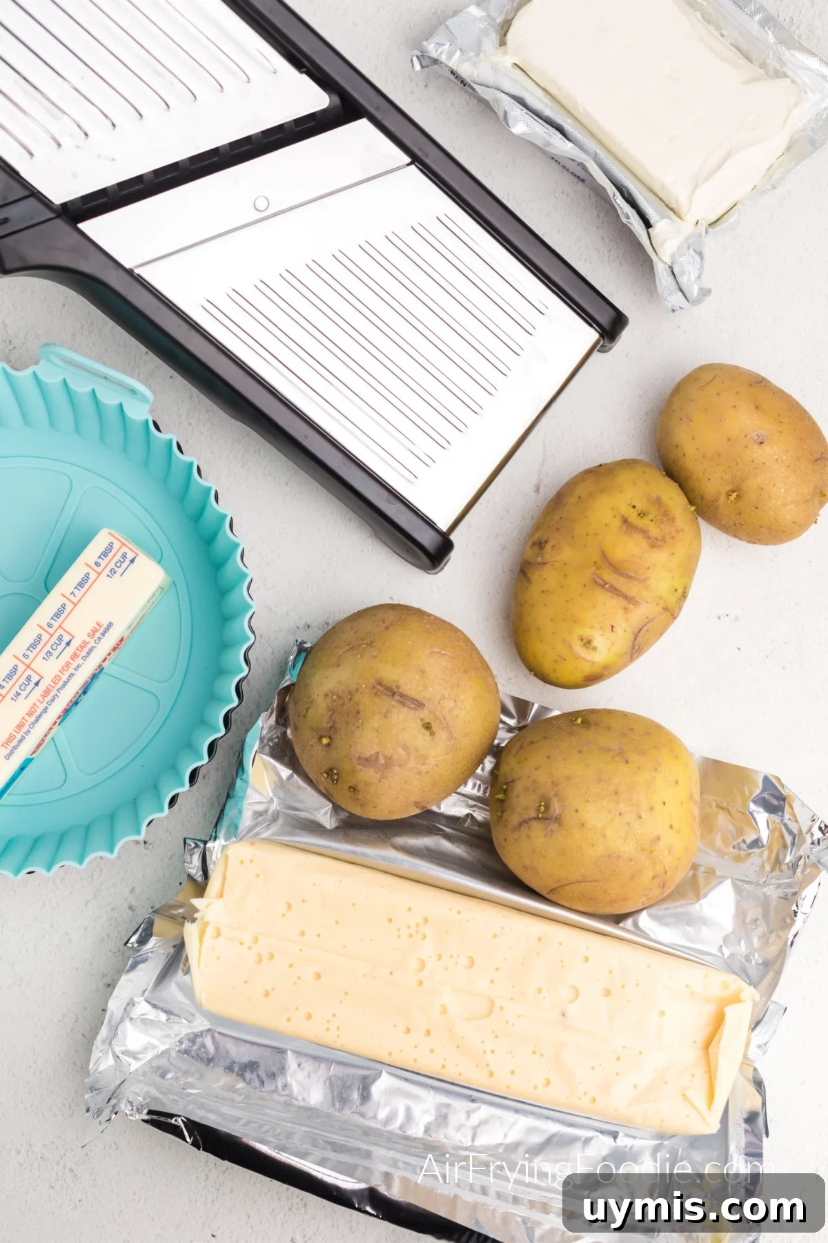 Air Fryer Scalloped Potatoes with Melted Cheese 3 Mandolin, silicone baking dish, cream cheese, butter, queso block cheese, and potatoes.