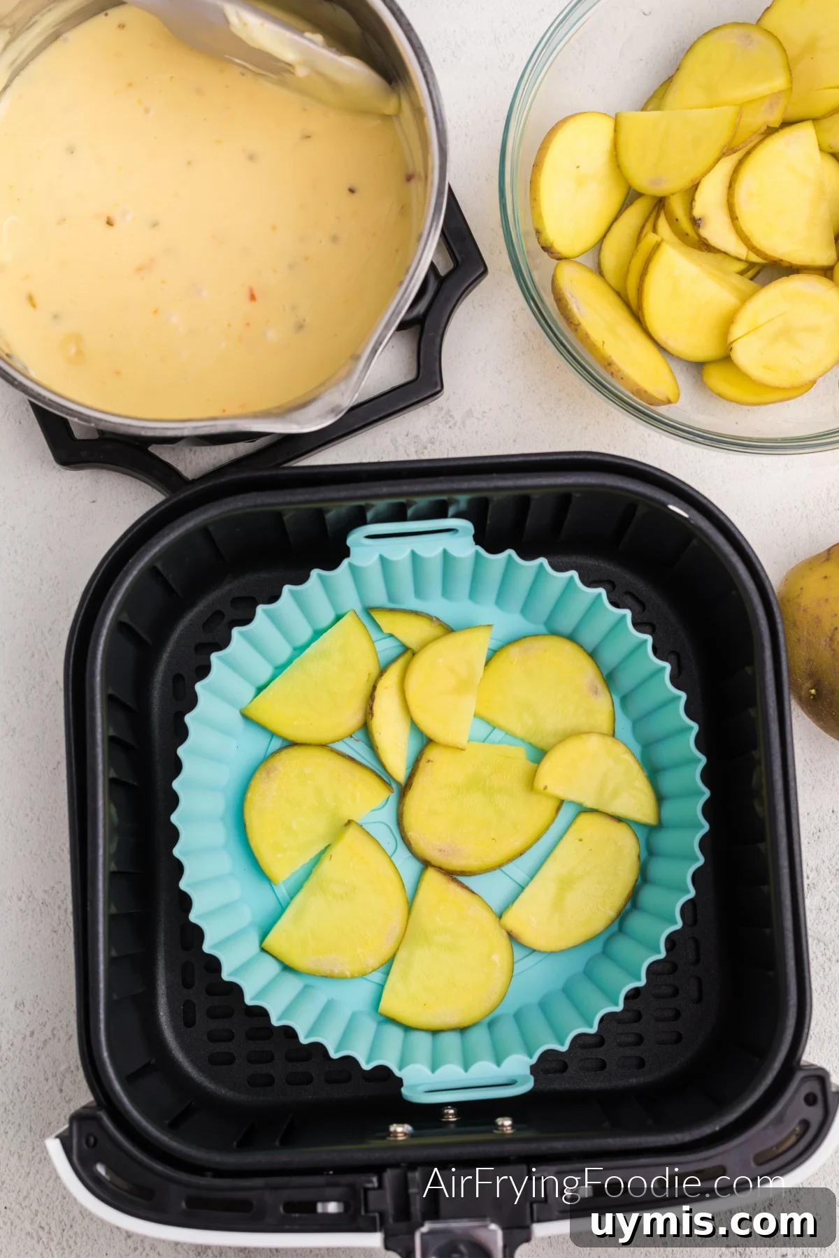 Air Fryer Scalloped Potatoes with Melted Cheese 7 Layer of sliced potatoes in the bottom of a silicone dish in the basket of the air fryer.