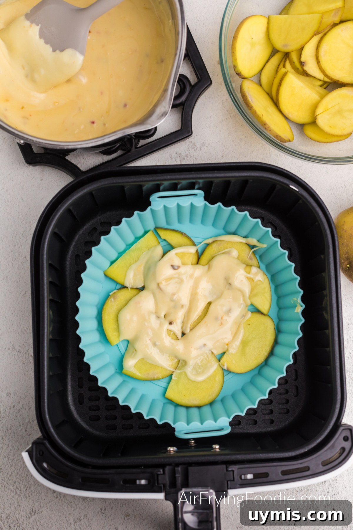 Air Fryer Scalloped Potatoes with Melted Cheese 8 Cheese mixture covering a layer of potatoes in the silicone baking dish.
