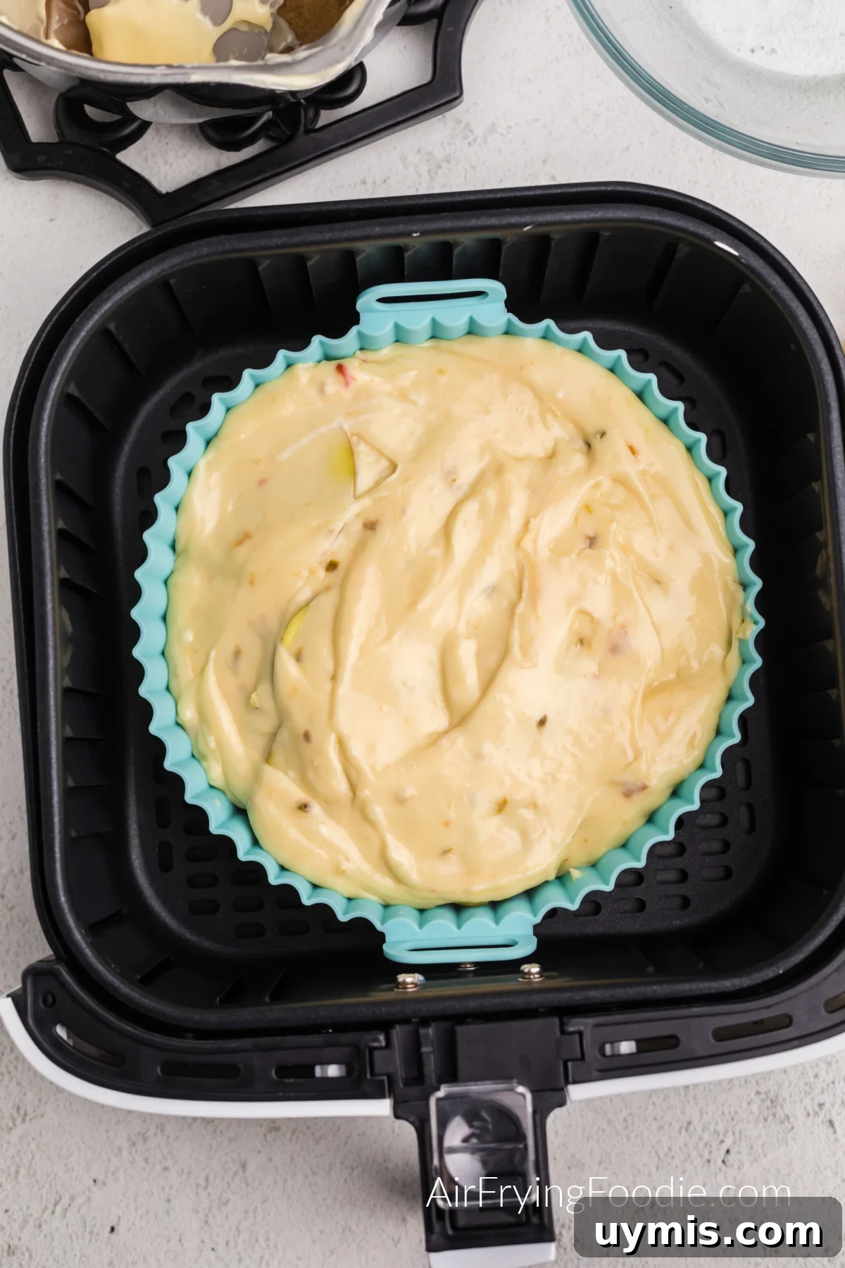 Air Fryer Scalloped Potatoes with Melted Cheese 9 Sliced potatoes a cheese layered in a silicone baking dish in the basket of the air fryer.